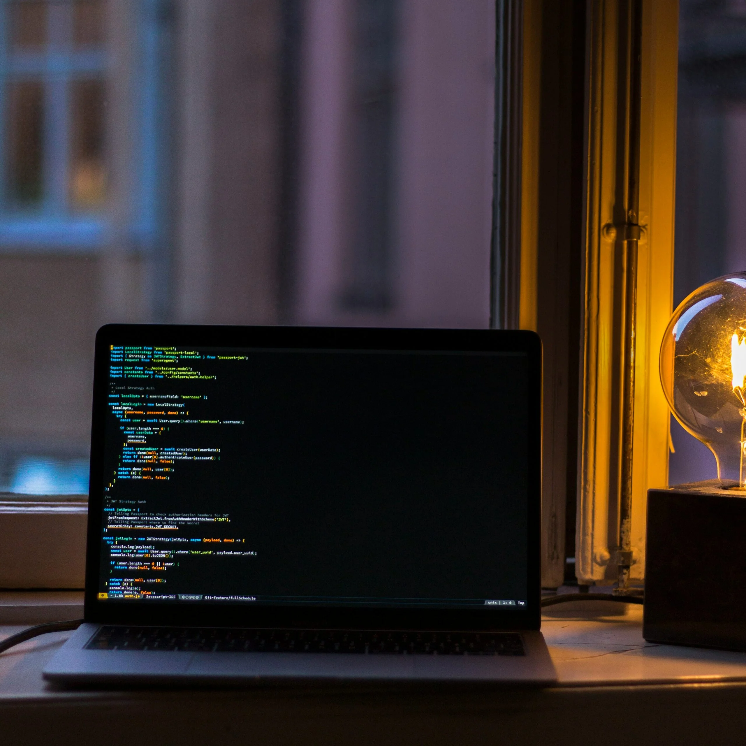 Laptop on a windowsill during an evening coding session, creating a cozy atmosphere.